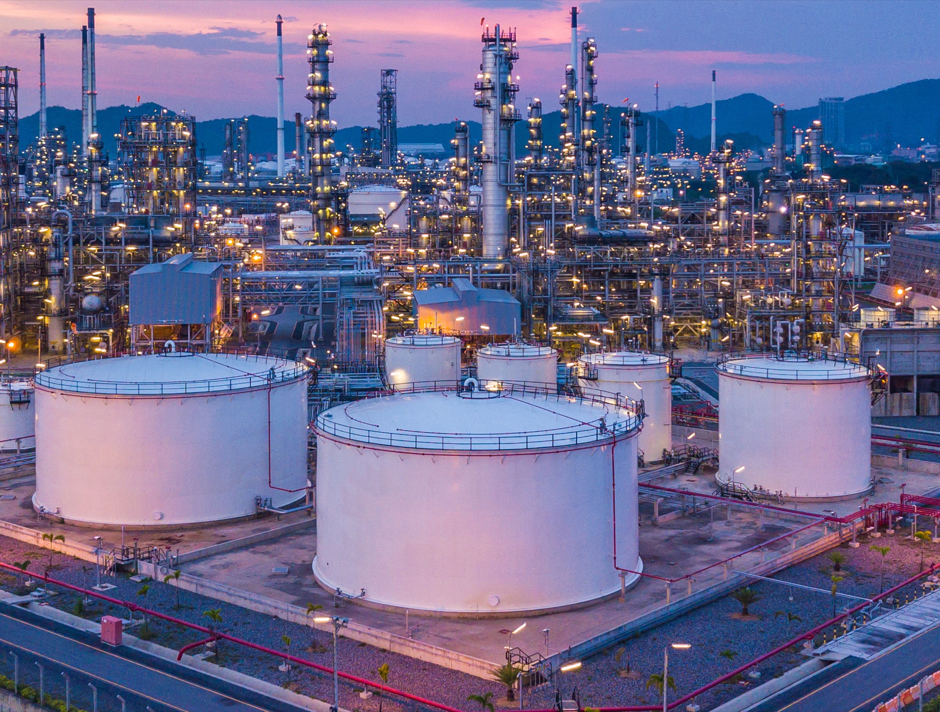 Oil refinery complex with large storage tanks and distillation towers at dusk