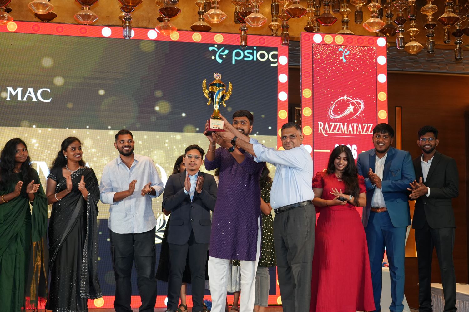 Team receiving award on stage with trophy and company logos in background